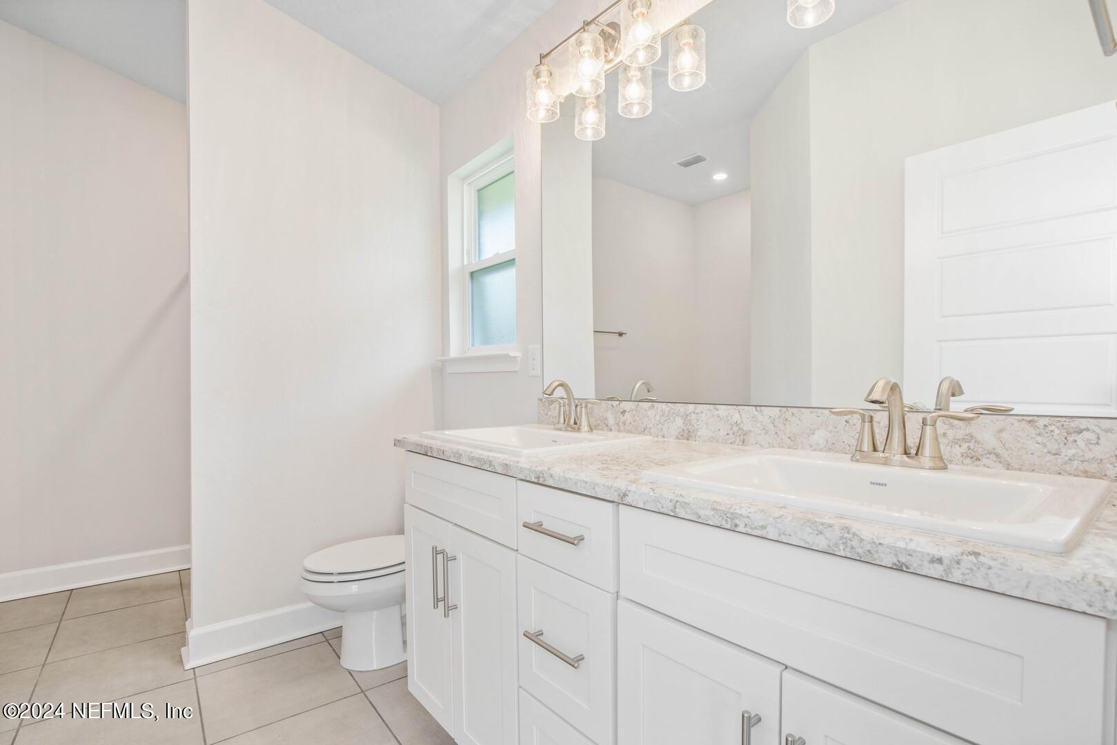 70 Rivertown Road Palm Coast, FL 32137 - Photo 19 of 25 a bathroom with a granite countertop sink a toilet and a mirror
