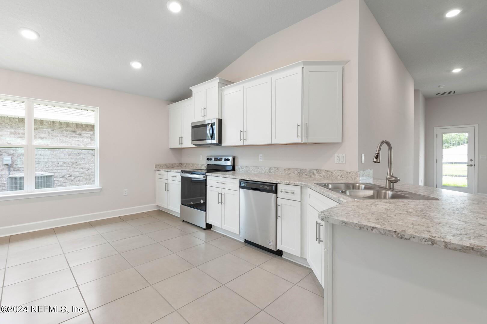 70 Rivertown Road Palm Coast, FL 32137 - Photo 7 of 25 a kitchen with granite countertop white cabinets and white appliances