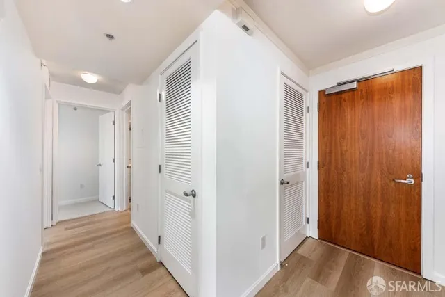 a view of a hallway with wooden floor and closet area