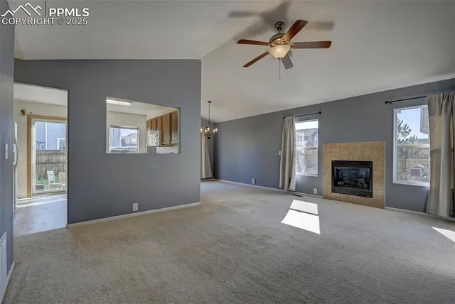 an empty room with windows and fireplace