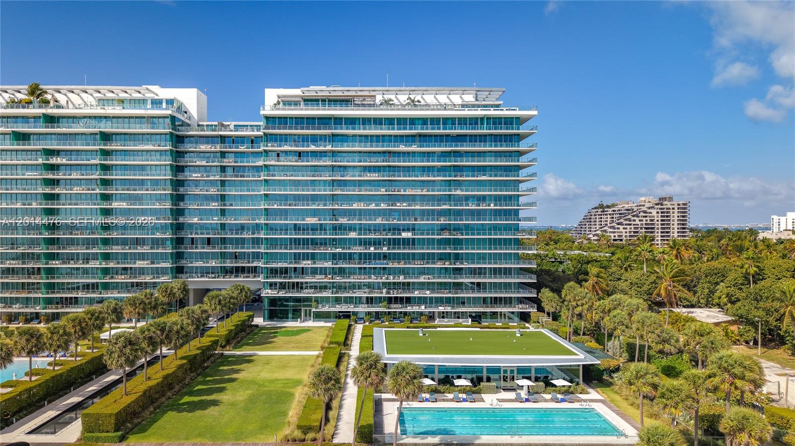 360 Ocean Drive, Unit 1106S Key Biscayne, FL 33149 - Photo 41 of 67 Exterior Building View – A full exterior view showcases the building’s contemporary glass façade, landscaped common areas, and nearby lap pool. The surrounding tropical greenery adds to the property’s polished resort-style setting.