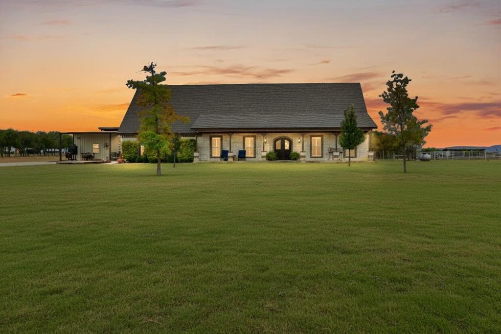a view of a big house with a big yard and large trees