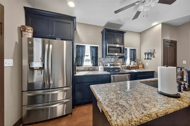 a kitchen with stainless steel appliances granite countertop a refrigerator a stove and a sink