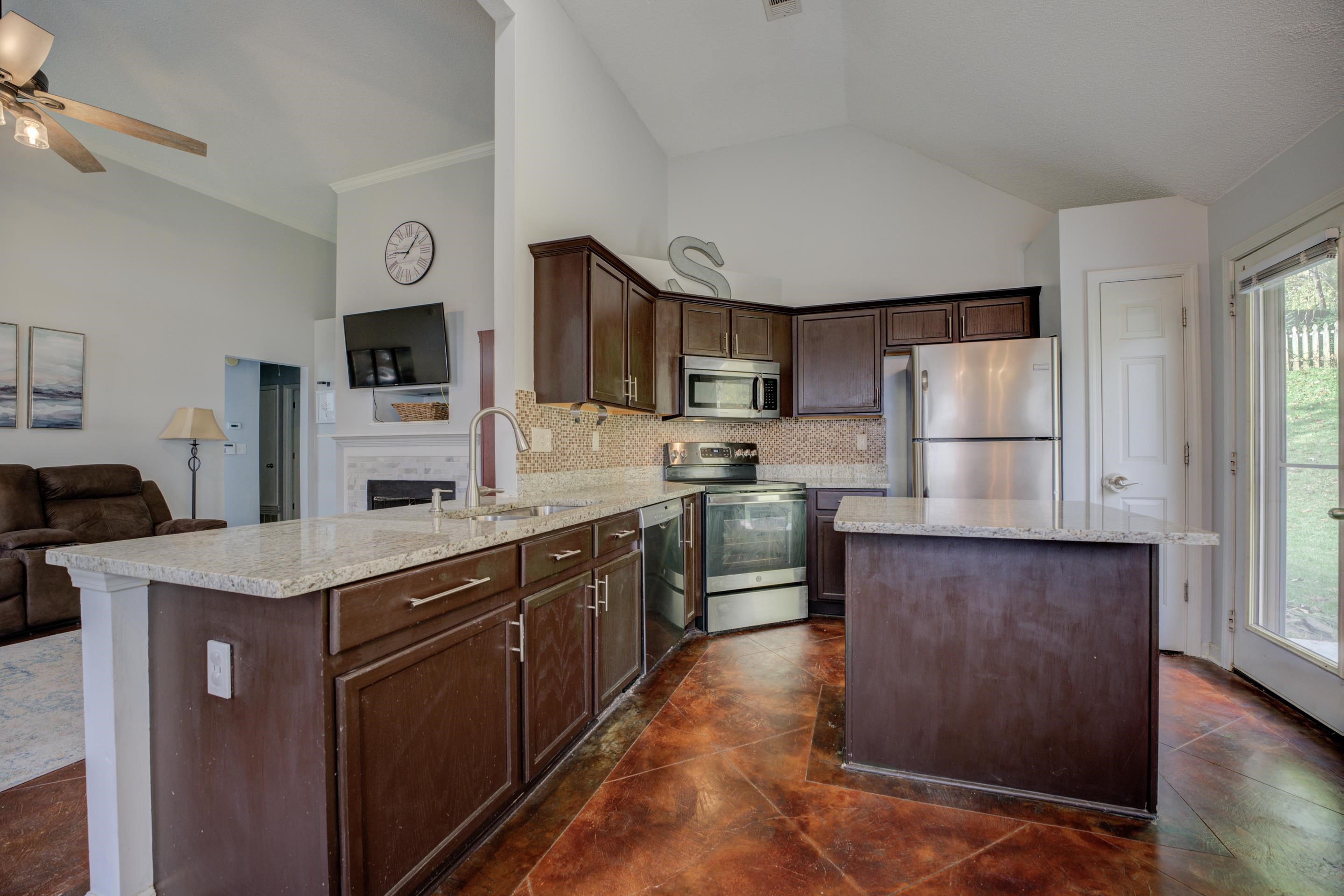 9696 Java Cove Memphis, TN 38002 - Photo 5 of 26 Kitchen with backsplash, desirable granite counters, kitchen island, appliances with stainless steel finishes, pantry and dark brown cabinetry.