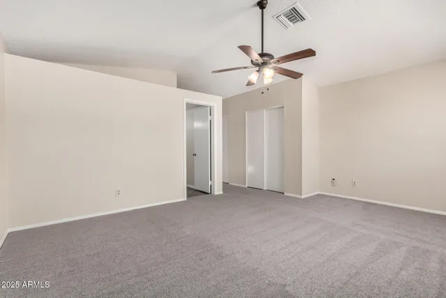 an empty room with closet and a chandelier fan