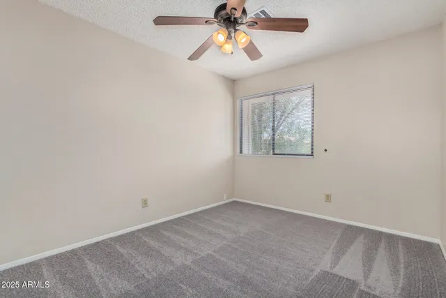 a view of an empty room and chandelier fan