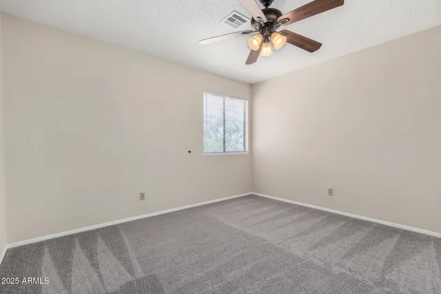 an empty room with a ceiling fan and a window