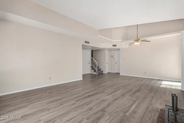 an empty room with windows and fan