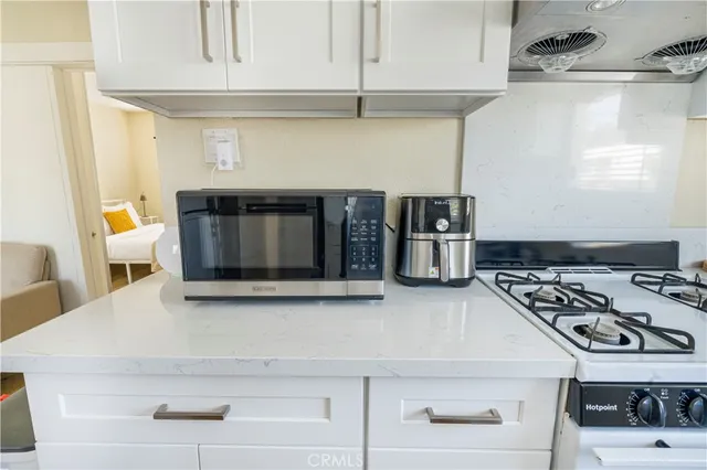 a kitchen with stainless steel appliances granite countertop a stove and a microwave with white cabinets