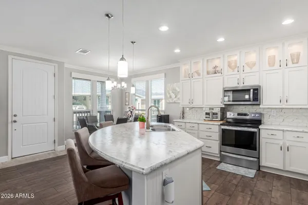 a kitchen with stainless steel appliances granite countertop a kitchen island hardwood floor sink stove dining table and chairs