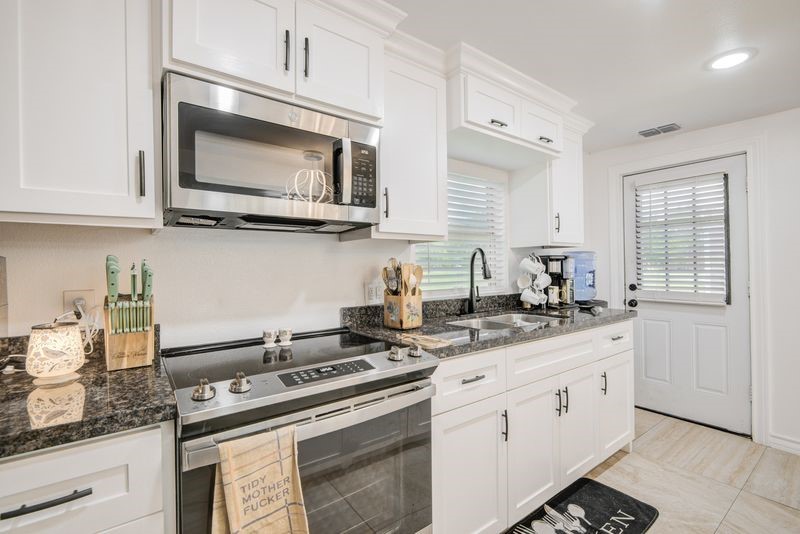 1256 2nd Street Clute, TX 77531 - Photo 14 of 43 a kitchen with white cabinets and appliances