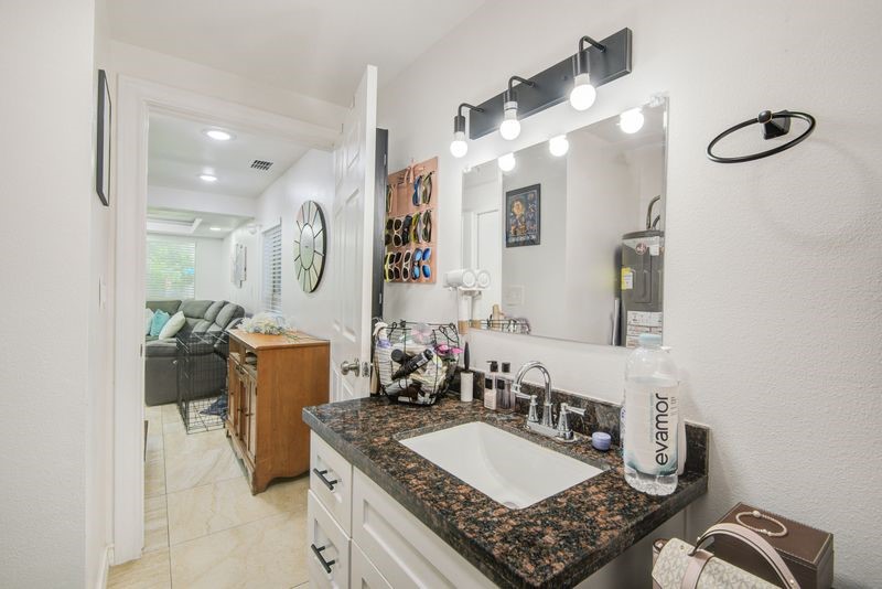 1256 2nd Street Clute, TX 77531 - Photo 25 of 43 a bathroom with a granite countertop sink a mirror a vanity and shower
