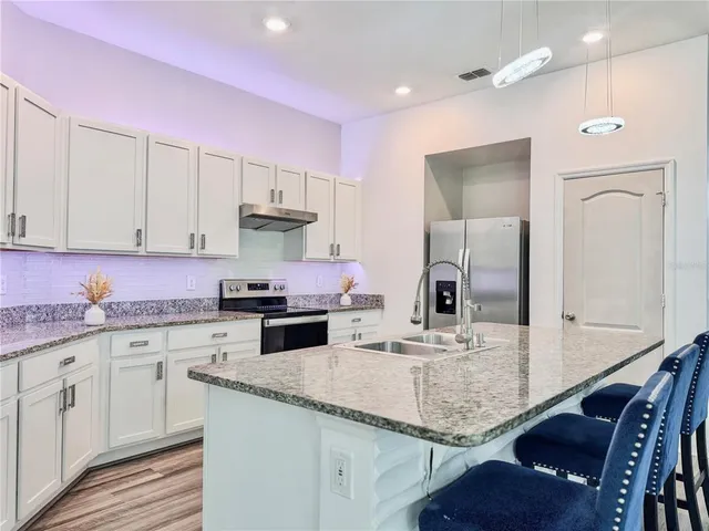 a kitchen with granite countertop stainless steel appliances a sink stove and refrigerator