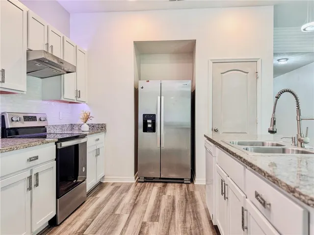 a kitchen with granite countertop cabinets stainless steel appliances and wooden floor