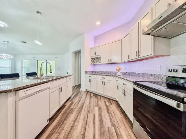 a bathroom with a granite countertop white cabinets and a potted plant