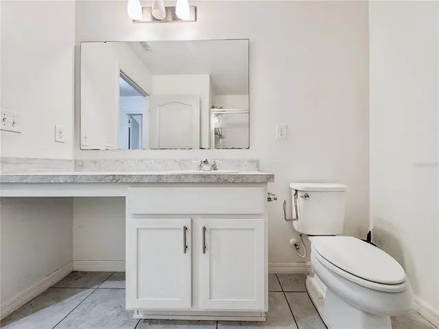 a bathroom with a granite countertop toilet sink and mirror