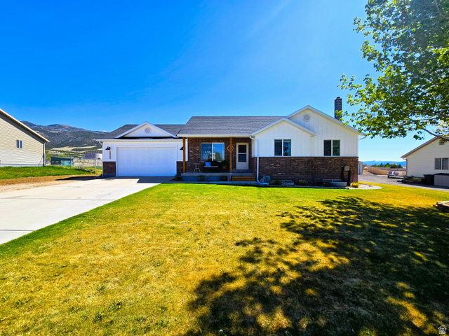 2026 Saddleback View Drive Enoch, UT 84721 - Photo 1 of 1 Ranch-style home with a porch, concrete driveway, brick siding, and a front lawn