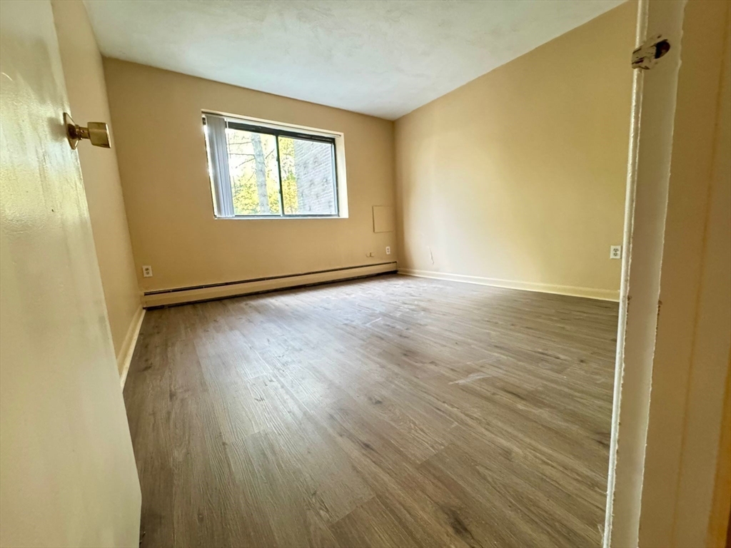 32 Whites Avenue, Unit E112 Watertown, MA 02472 - Photo 13 of 41 an empty room with wooden floor and windows