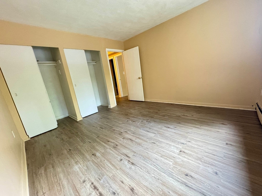 32 Whites Avenue, Unit E112 Watertown, MA 02472 - Photo 14 of 41 an empty room with wooden floor and door