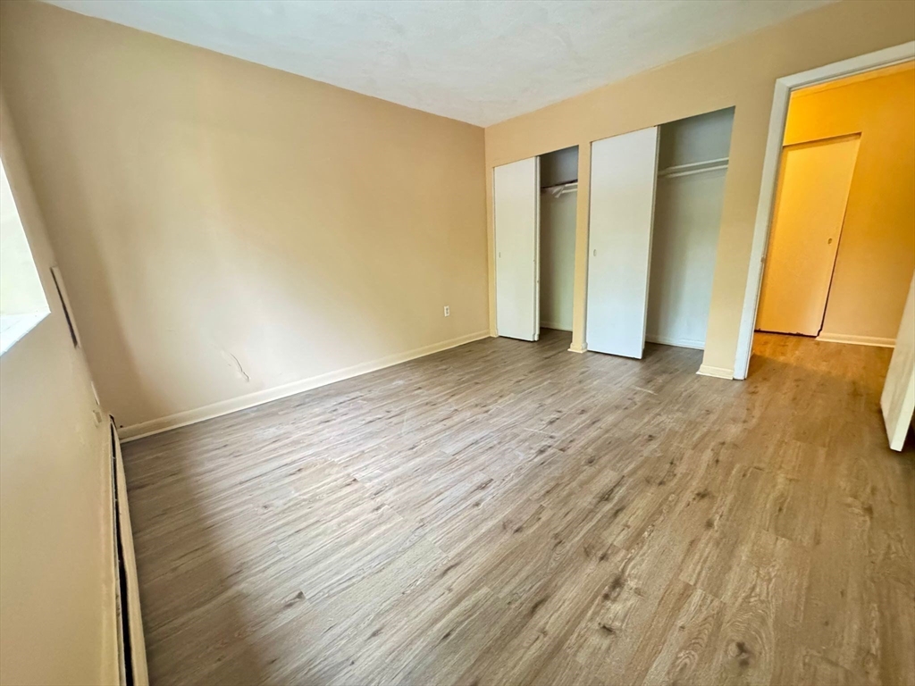 32 Whites Avenue, Unit E112 Watertown, MA 02472 - Photo 17 of 41 a view of an empty room with wooden floor and a window