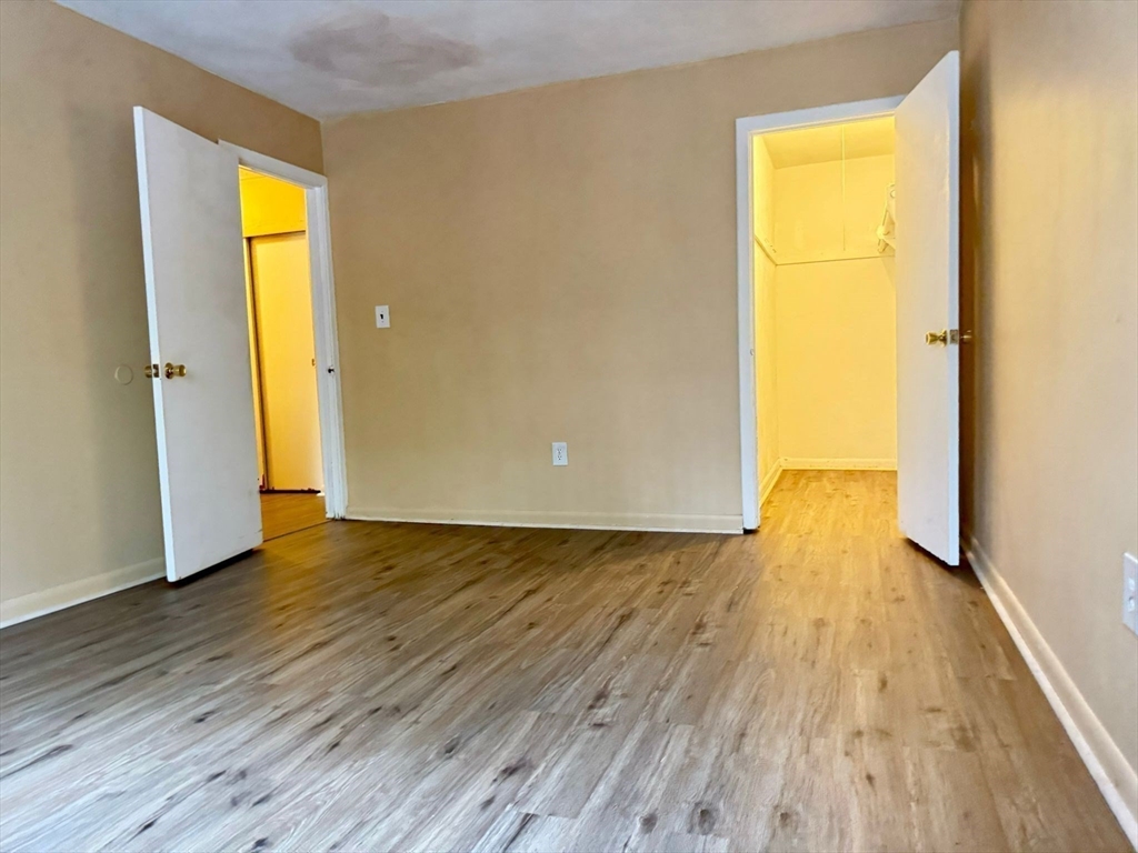 32 Whites Avenue, Unit E112 Watertown, MA 02472 - Photo 21 of 41 a view of an empty room with wooden floor and a window
