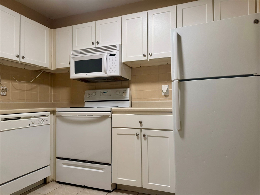 32 Whites Avenue, Unit E112 Watertown, MA 02472 - Photo 9 of 41 a kitchen with stainless steel appliances white cabinets and a refrigerator