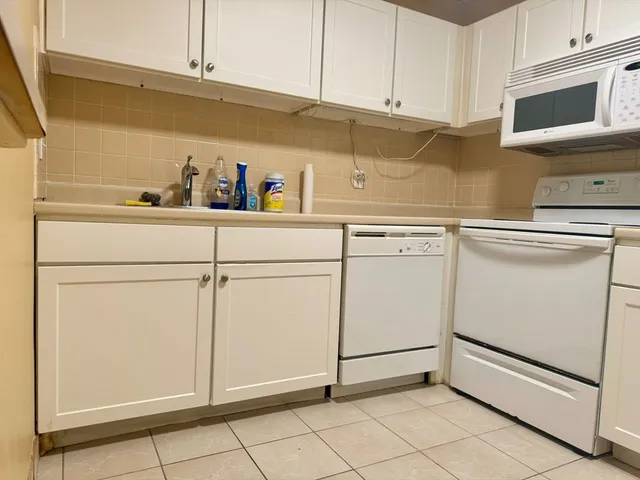 a kitchen with white cabinets and white appliances