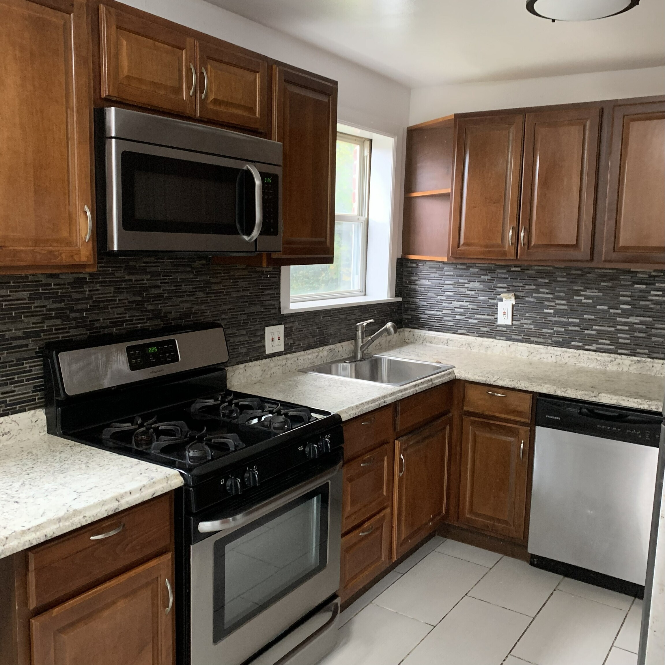 11 Bedford Avenue, Unit J1 Norwalk, CT 06850 - Photo 3 of 10 a kitchen with granite countertop stainless steel appliances a sink stove and microwave