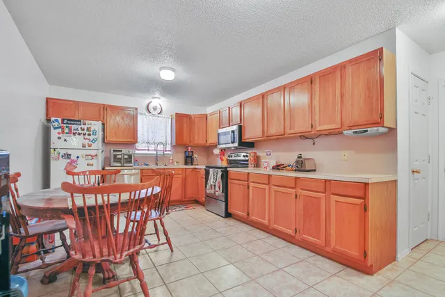 a kitchen with stainless steel appliances wooden cabinets granite counter tops and a view of living room