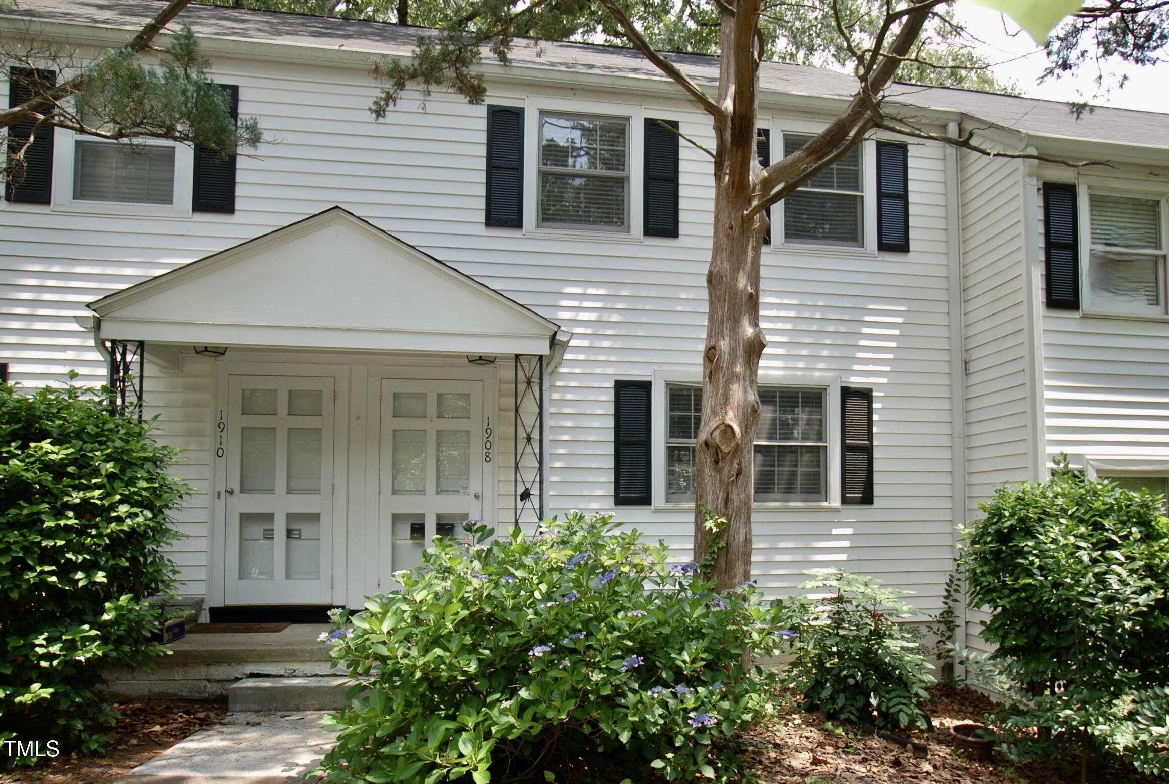 a view of a white house with large windows and flower plants