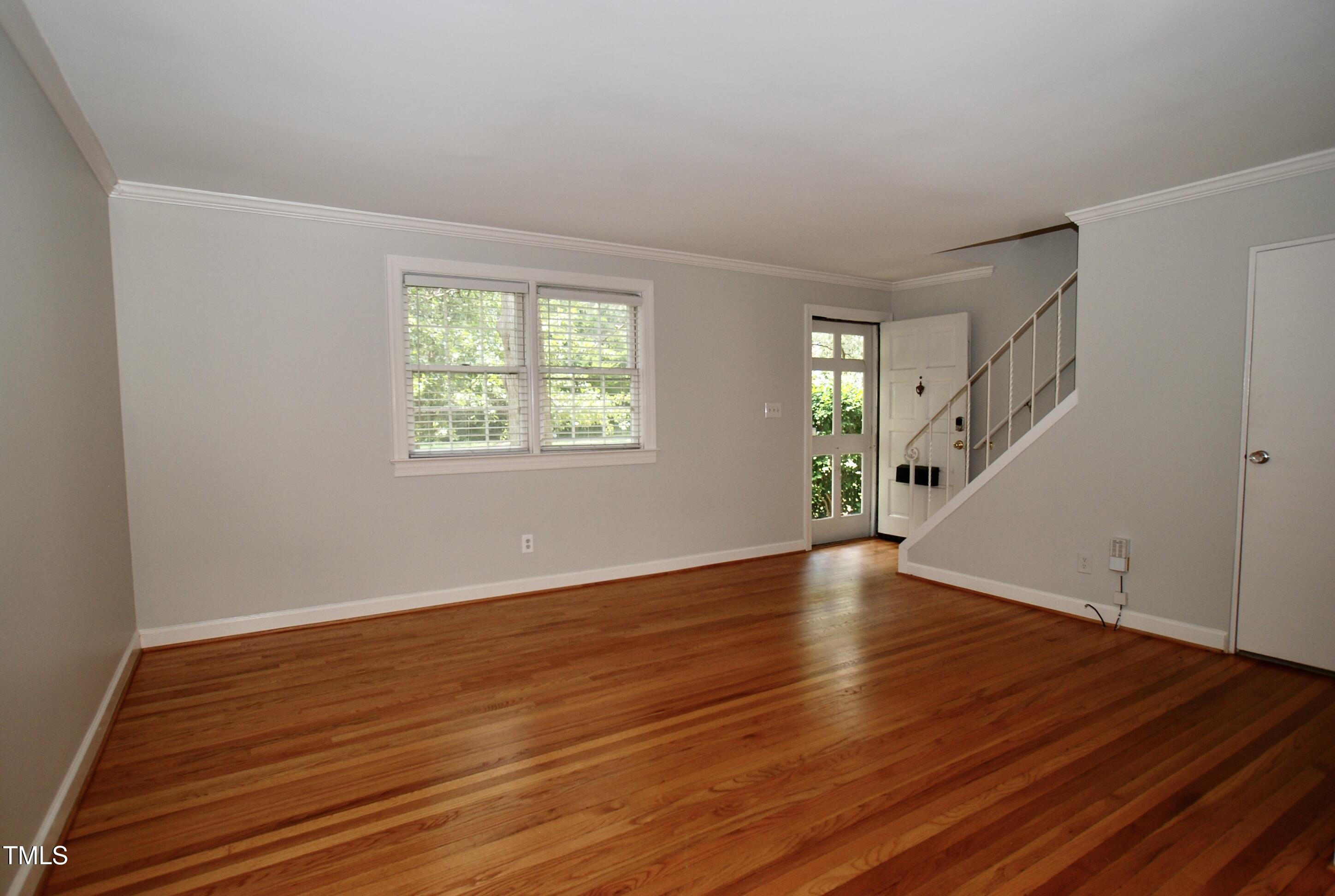 1908 Smallwood Drive Raleigh, NC 27605 - Photo 4 of 30 a view of an empty room with wooden floor and a window