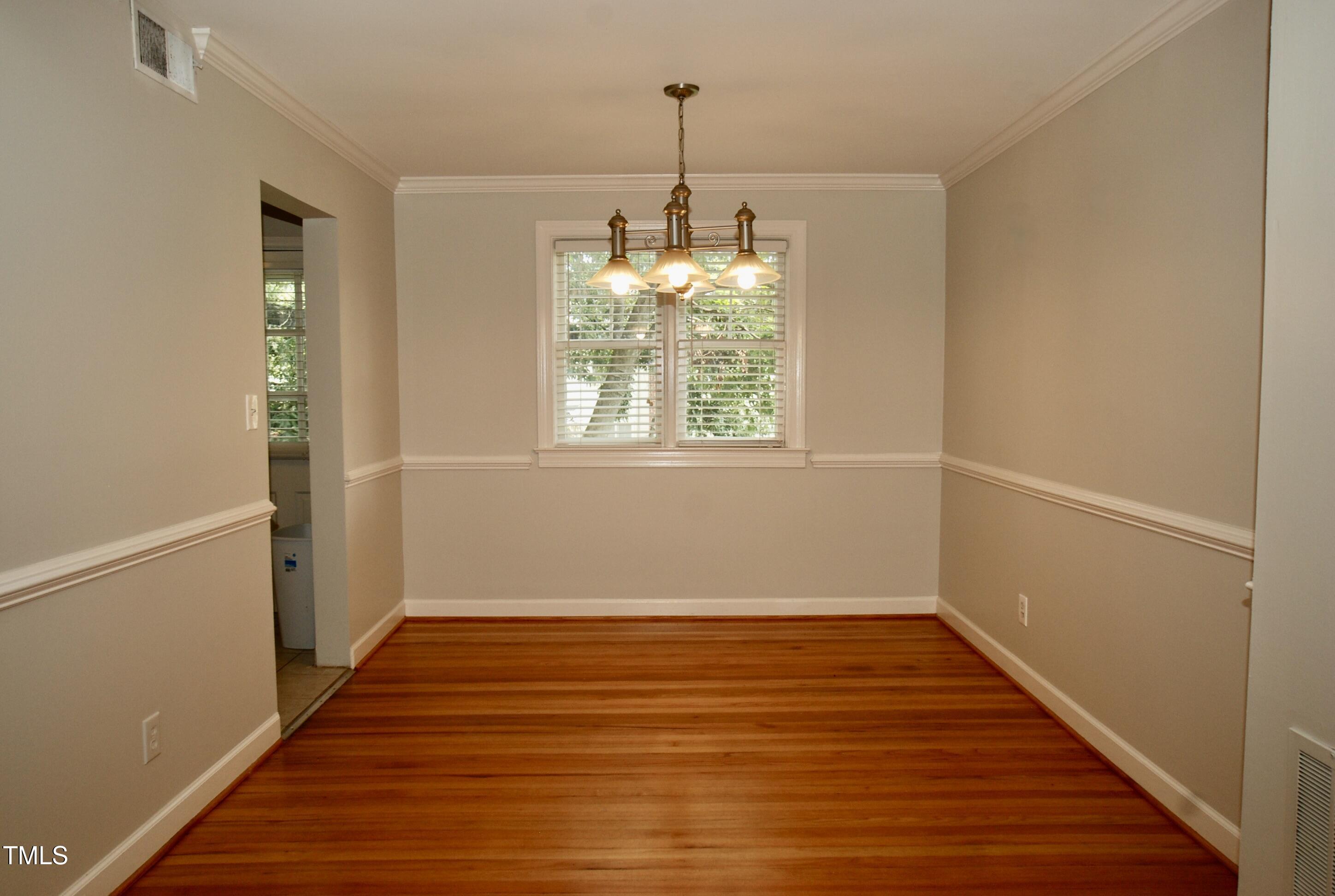 1908 Smallwood Drive Raleigh, NC 27605 - Photo 5 of 30 a view of an empty room with wooden floor and a window