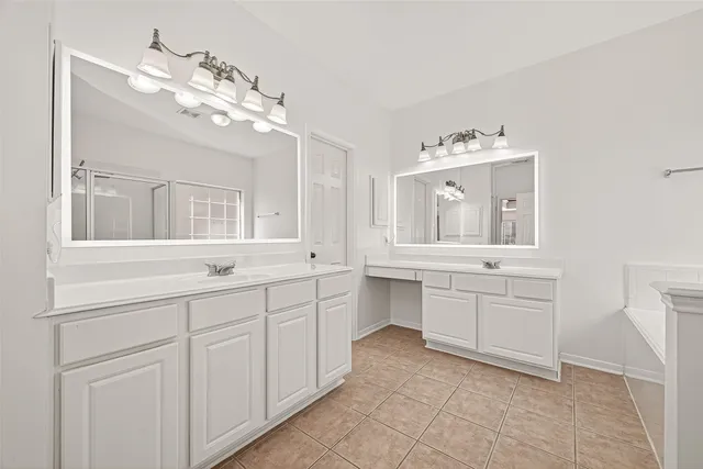a bathroom with a double vanity sink mirror and bathtub