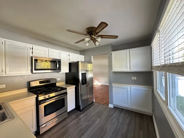 a kitchen with stainless steel appliances a stove a microwave and a hard wood floor