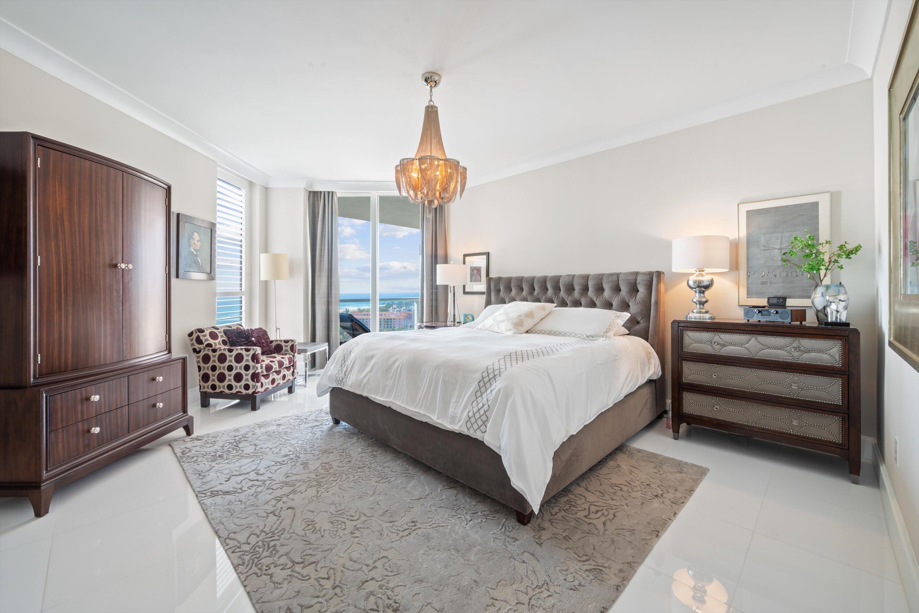 2700 North Ocean Drive, Unit 1401B Singer Island, FL 33404 - Photo 19 of 49 a bedroom with a large bed and a chandelier