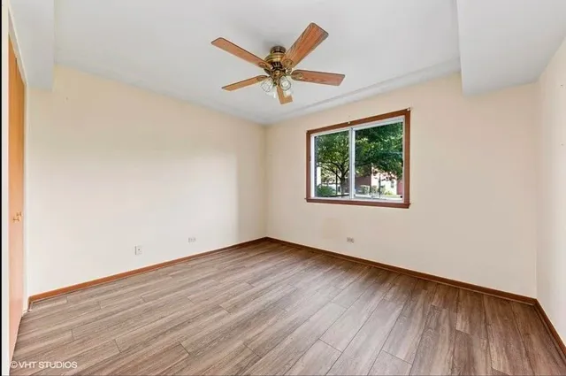 an empty room with wooden floor windows and fan