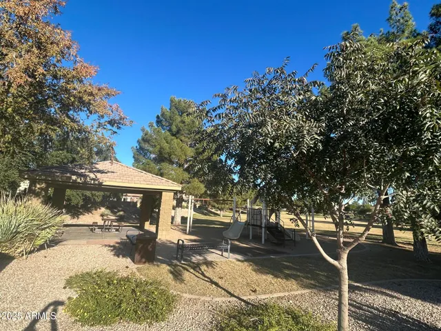 a view of a patio with table and chairs under an umbrella with large trees