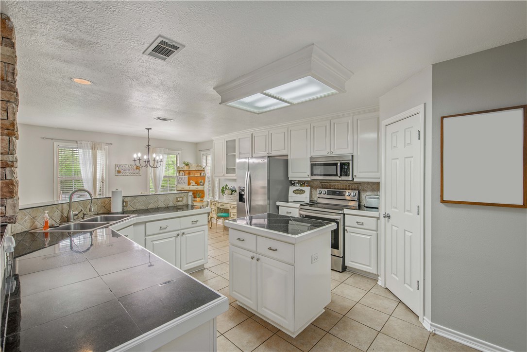 6538 Olympia Buddy Road College Station, TX 77845 - Photo 18 of 50 a kitchen with white cabinets and stainless steel appliances