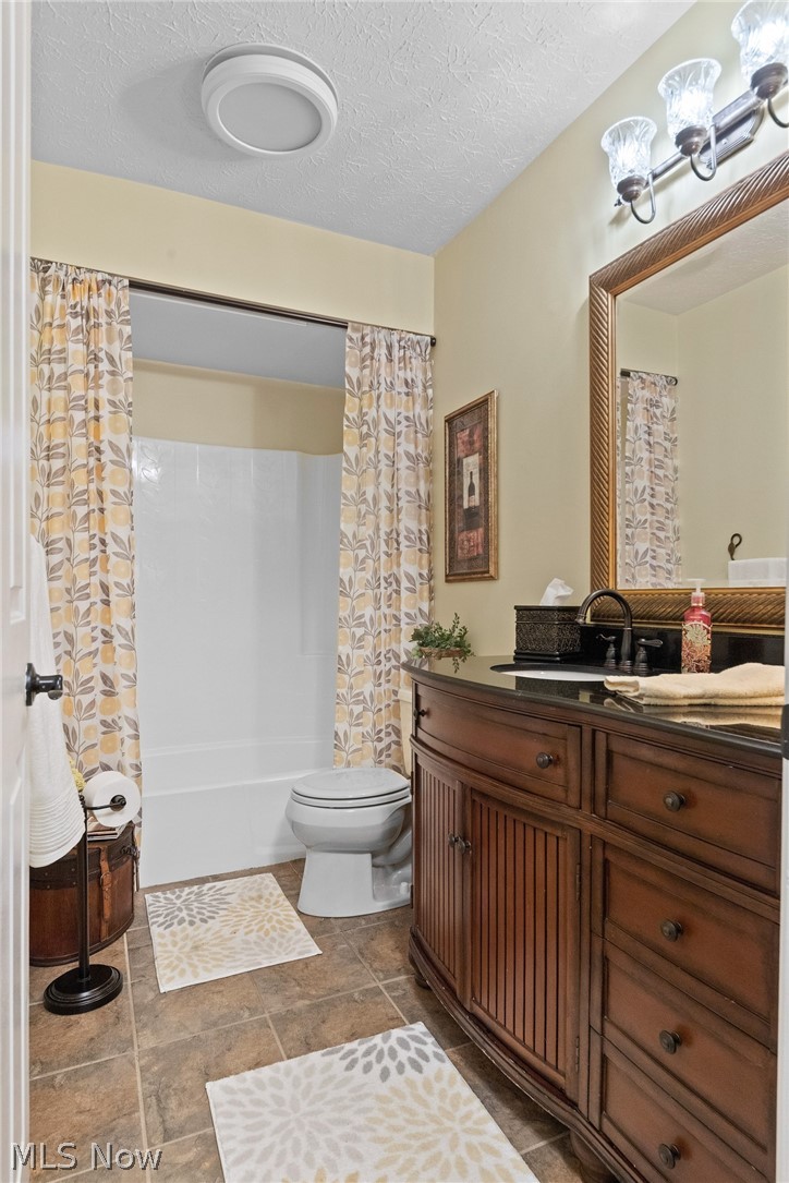 171 Granger Road, Unit 107 Medina, OH 44256 - Photo 21 of 41 2nd level Full Bathroom featuring a dark wood-finish vanity with a black countertop, a framed wall mirror, a white bathtub with shower, and tile flooring