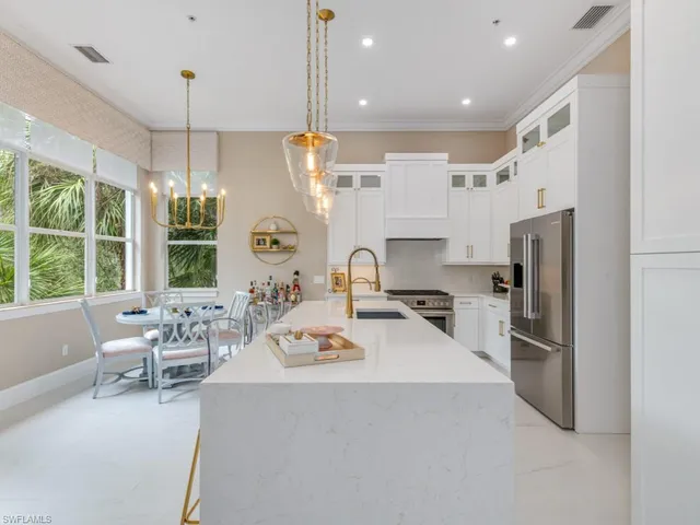 a kitchen with stainless steel appliances a refrigerator a stove top oven a sink and chairs