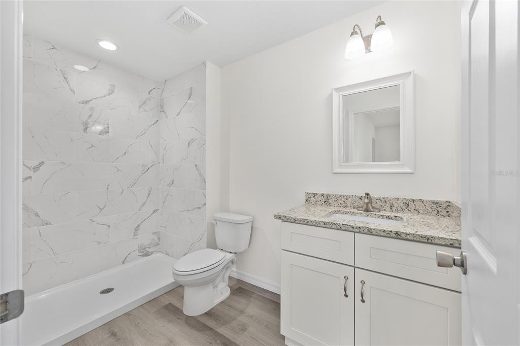 13019 Northeast 7th Loop Silver Springs, FL 34488 - Photo 27 of 35 a bathroom with a granite countertop sink a toilet and shower
