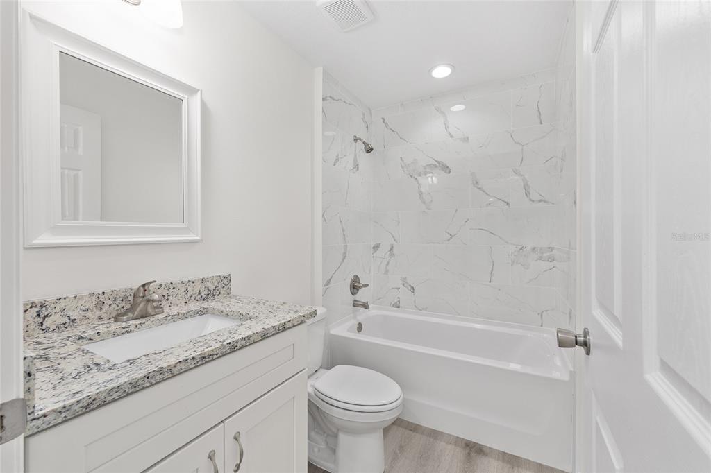 13019 Northeast 7th Loop Silver Springs, FL 34488 - Photo 31 of 35 a bathroom with a granite countertop sink a toilet and a bathtub