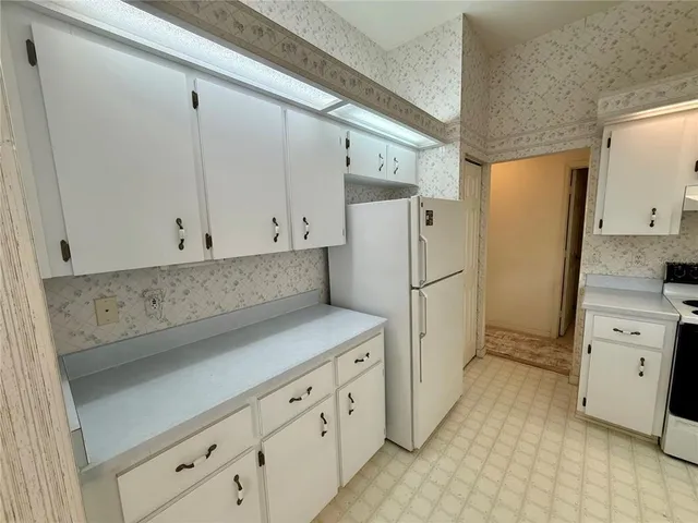 a kitchen with white cabinets and refrigerator