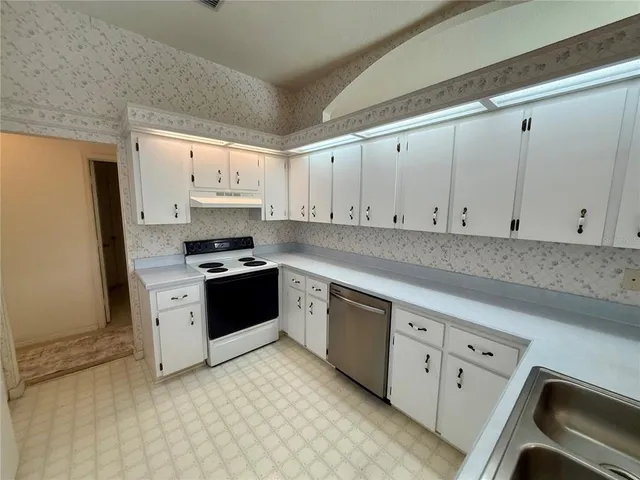 a kitchen with granite countertop white cabinets and white appliances