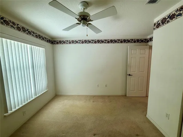 en empty room with a ceiling fan and window
