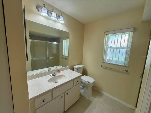 a bathroom with a granite countertop sink a toilet and a mirror