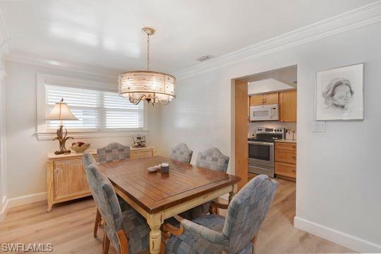 265 Yorkshire Court, Unit 8 Naples, FL 34112 - Photo 20 of 33 Dining space featuring crown molding, a chandelier, and light wood-style floors