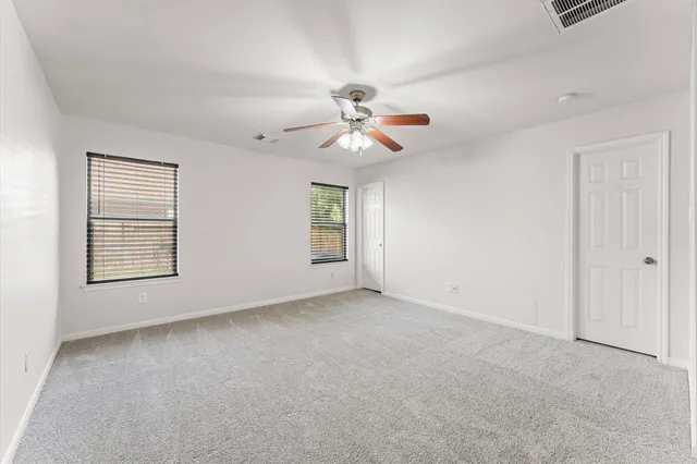 an empty room with windows and fan