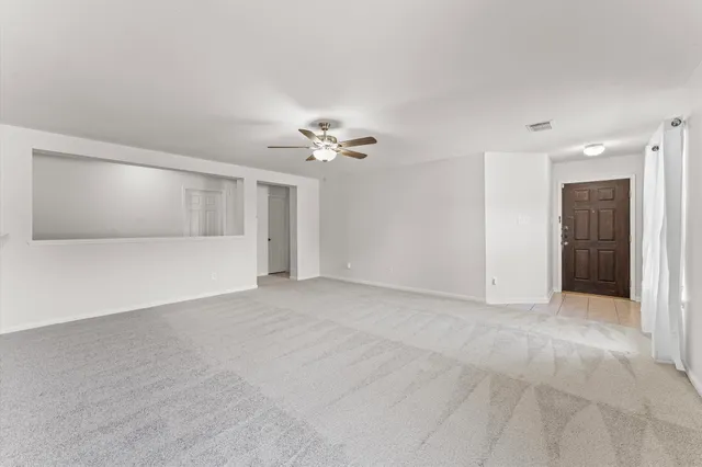 a view of an empty room with a chandelier fan
