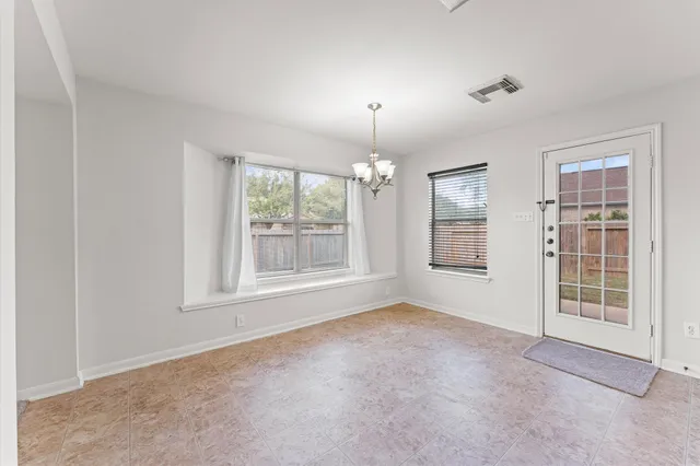 an empty room with windows and chandelier fan